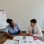 coworkers sitting at a table with documents and talking